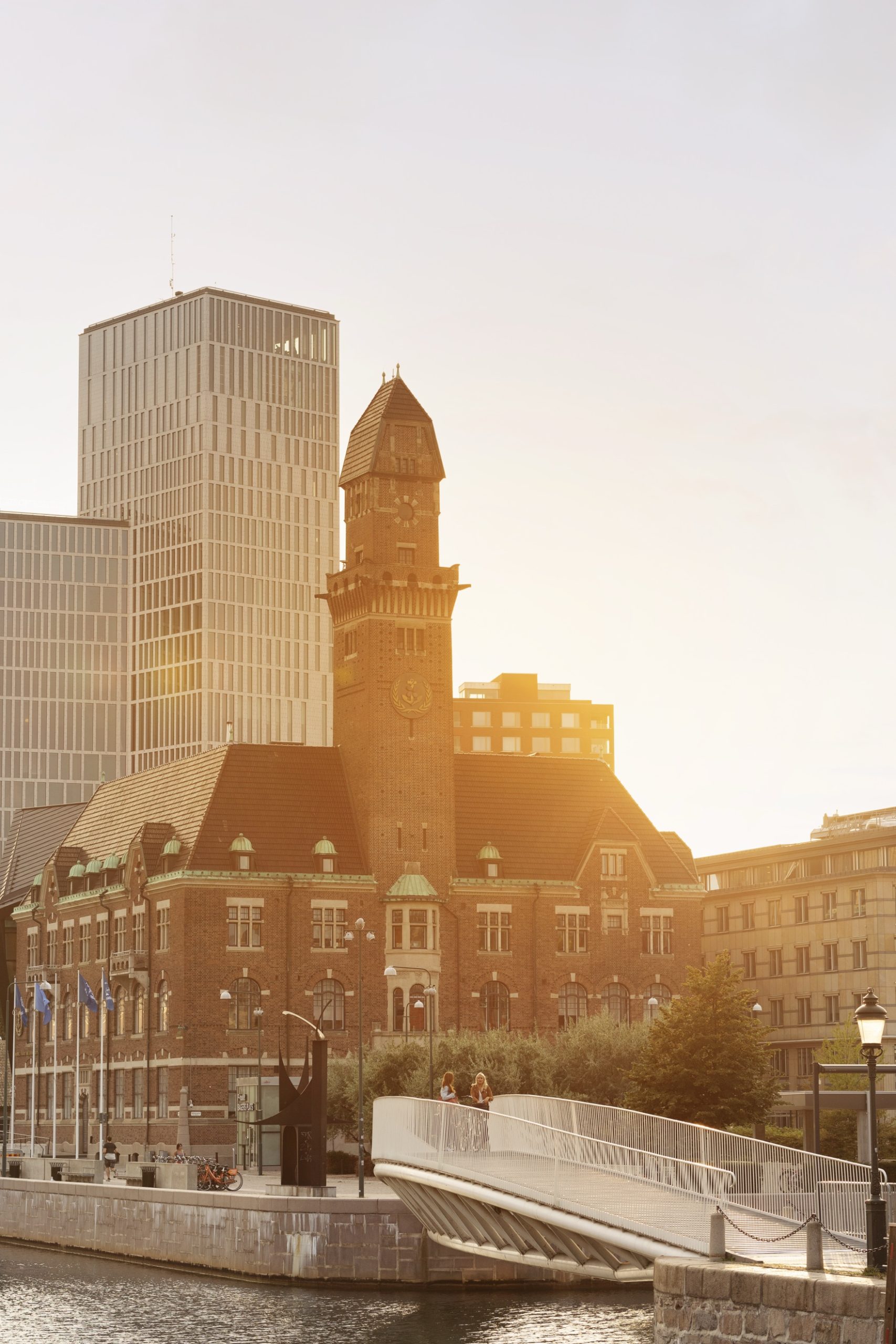 Historic clock tower and civic buildings beside a canal at sunset