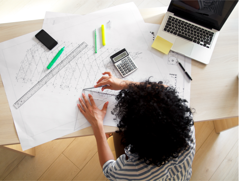 Architect reviewing structural drawings and cost calculations at a desk